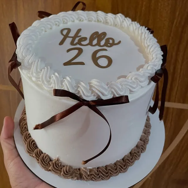 Bolo branco com laços de cetim marrom e base de chocolate